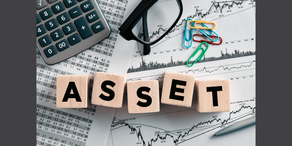 Atop a shuffled stack of financial papers sits a calculator, pair of eyeglasses, group of multicoloured paper clips, and small wooden tiles that spells out the word "Asset."