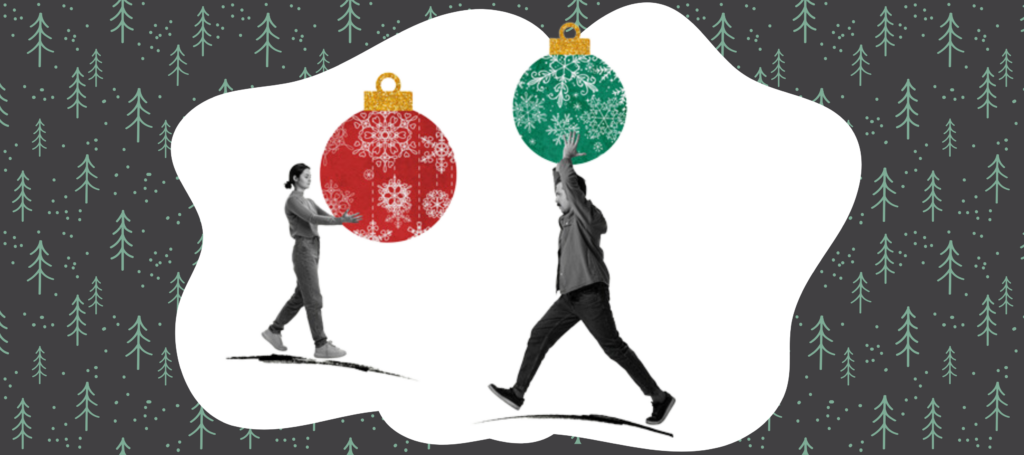 A woman and man carry large christmas baubles as they walk.