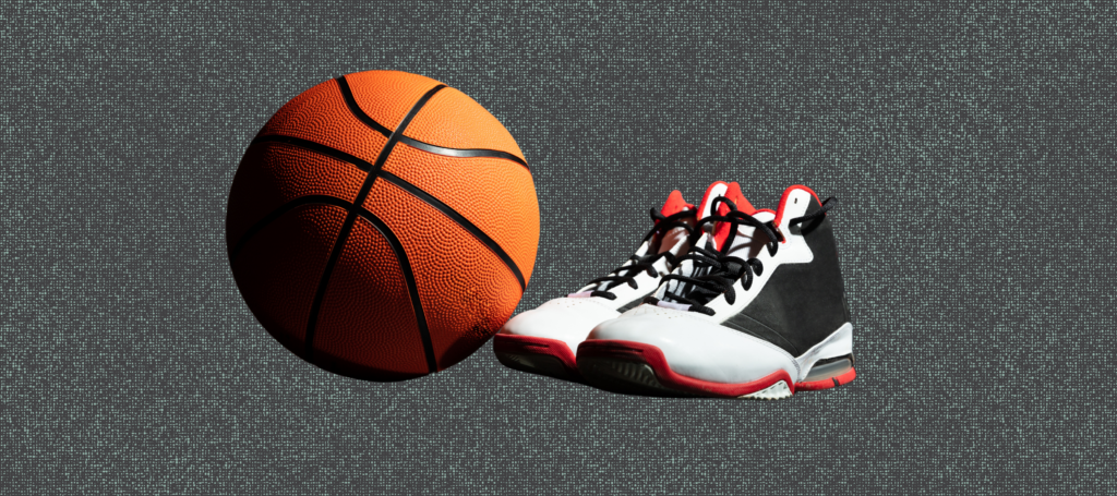 A pair of sneakers sit next to a basketball.